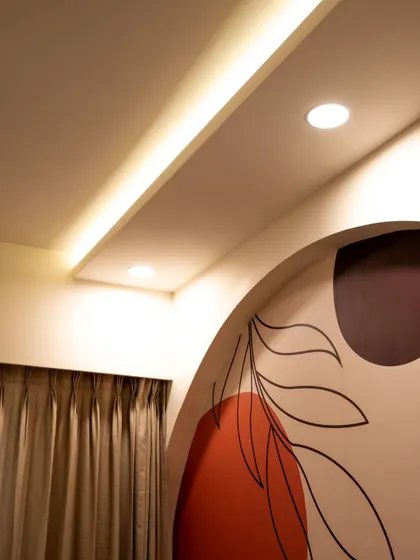 A close-up of cove lighting and downlights in a room with a modern, artistic wall mural.