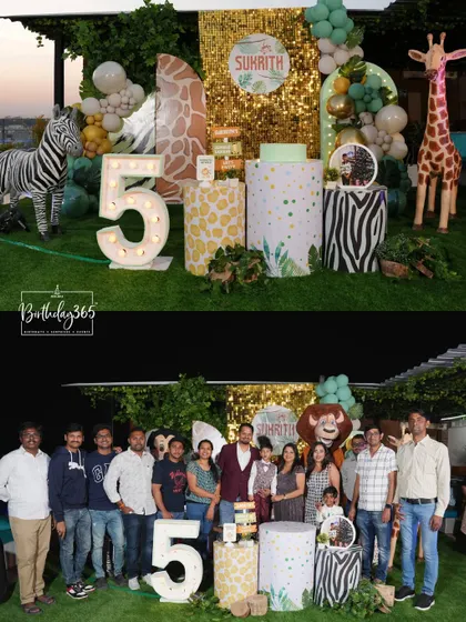 A wild rooftop safari for Sukrith's 5th birthday. The decor included a shimmering gold backdrop, animal-print pedestals, a large marquee number "5", and life-sized zebra and giraffe props.