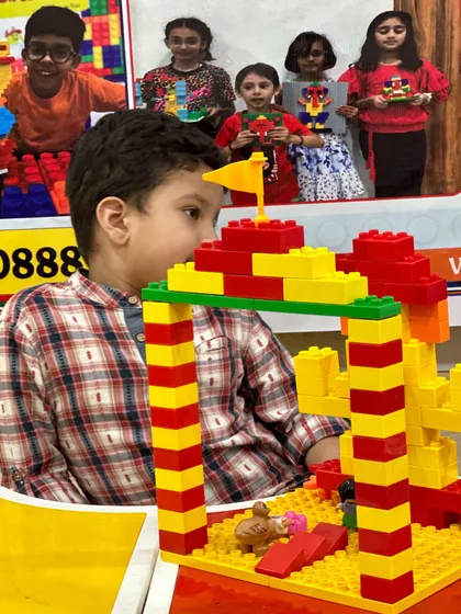 A close-up shot of a student carefully placing a block on his creation, capturing the focus required in LEGO engineering.