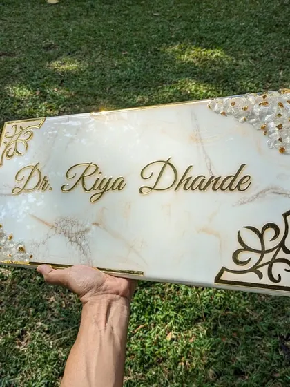 The goal here was to create a resin nameplate that looks just like real marble. This 10 by 20-inch piece for a doctor's office features a subtle white and gold marble effect, accented with natural stones and decorative golden corners for a professional and elegant finish.