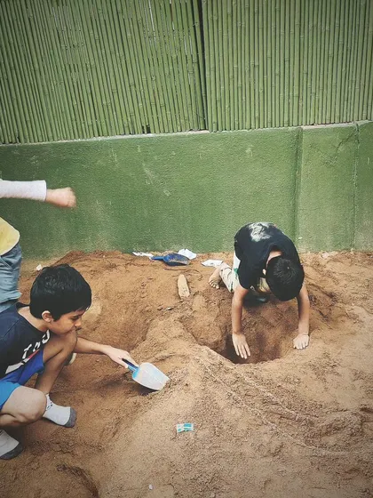 Children dig and sculpt in the sandpit, completely absorbed in their work. This is a space for both individual focus and collaborative creation.