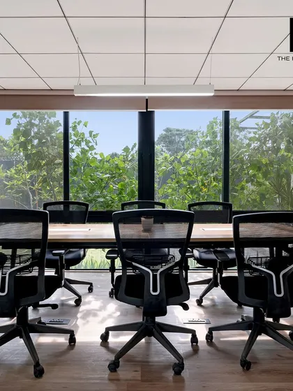 This conference room is designed to bring the outside in, with a large picture window that frames the lush green foliage. Natural light and views of nature are known to boost creativity and well-being at work.