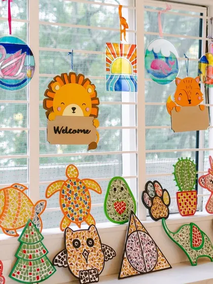 A collection of finished mosaic and painted suncatchers hanging in the window. These pieces look stunning when the light shines through them.