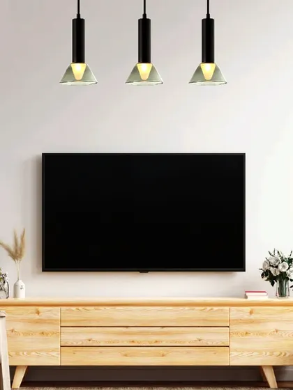 A trio of modern industrial-style pendants hangs over a media console. This linear arrangement provides excellent task lighting while bringing a new dawn of artful, luxury lighting to the space.