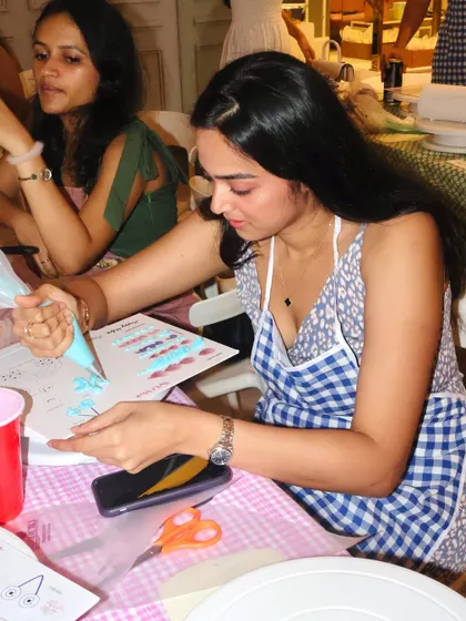 A guest at our workshop carefully practicing her buttercream piping techniques on a guide sheet before starting on her cake.