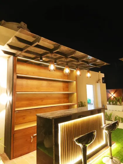 The custom-built bar at the Sushant Lok project, with open shelving, a marble countertop, and warm ambient lighting.