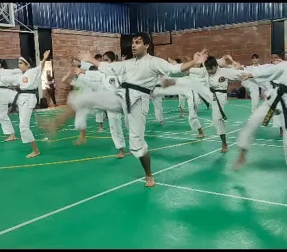 A group of students practicing balance and kicking drills during their belt exam.