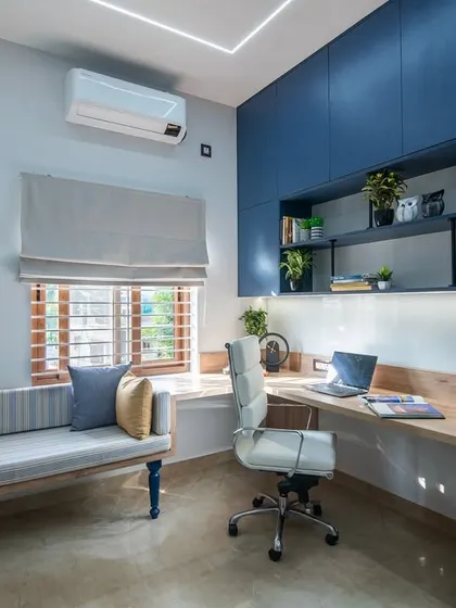This angle showcases the ample storage in the study room, with deep blue overhead cabinets and open shelves. The window seat and L-shaped desk create a highly functional and comfortable environment.