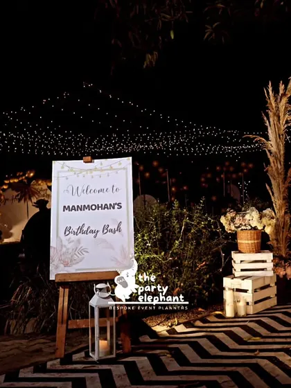 This shot captures the full entrance experience, from the welcome sign and chevron walkway to the pampas grass arch and the twinkling lights in the distance.
