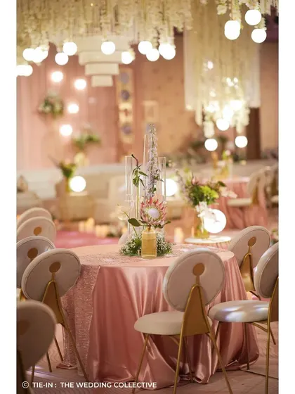 The guest tables were designed with the same whimsical elegance, featuring tall, modern centerpieces and glowing orbs. The pink satin tablecloths and contemporary chairs tied the entire look together, creating a cohesive and sophisticated dining experience.