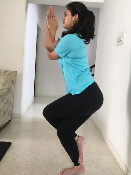 A student holds Garudasana (Eagle Pose), a balancing posture that stretches the hips, thighs, and shoulders while improving focus.