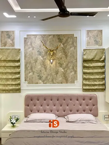 A direct view of the bed and headboard wall, showcasing the symmetrical design with Roman blinds and a decorative stag head light fixture.