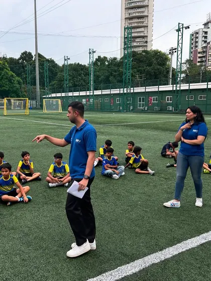 A sports psychologist from our partner Mpower Minds gives a talk to our young players, who are seated on the pitch. This session is part of our holistic approach to player development.