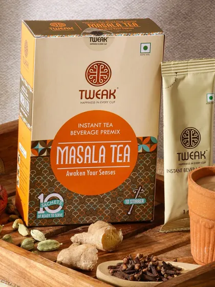 A rustic and authentic styling for Masala Tea. The use of a wooden tray, a traditional clay kullad, and whole spices like ginger and cloves instantly communicates the tea's flavor profile.