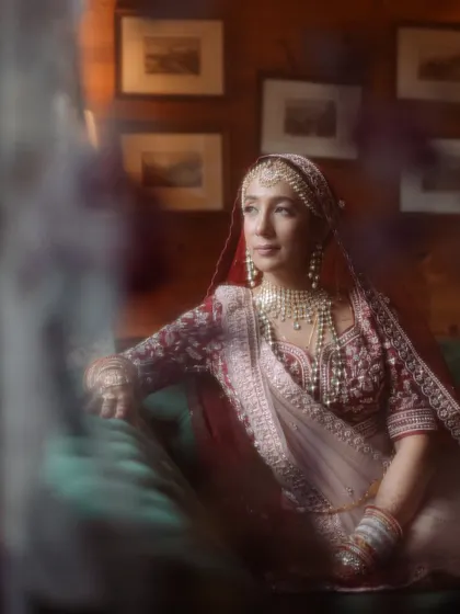 A soft, artistic portrait of the bride in her wedding finery, seated indoors, with a dreamy blur effect creating a timeless, painterly feel.