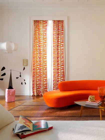 We embrace color as a powerful form of expression. This vibrant living area showcases how a fearless approach to design, pairing a bold, sculptural sofa with graphic embroidered curtains, can create a space that is energetic, modern, and full of personality.
