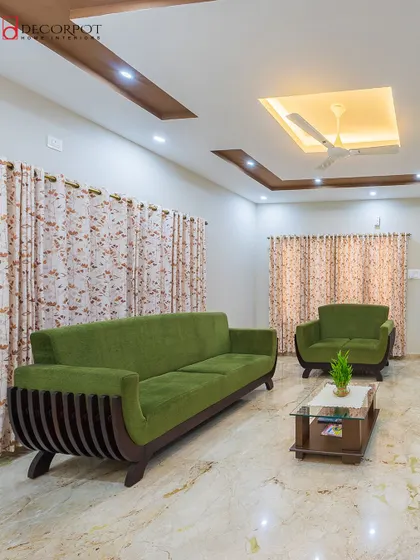 A simple yet elegant living room with a unique curved-arm wooden sofa in a striking green fabric. The marble flooring and simple decor keep the focus on the statement furniture.