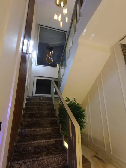 A view from the bottom of the stairs, looking up at the double-height space and the cascading chandelier.
