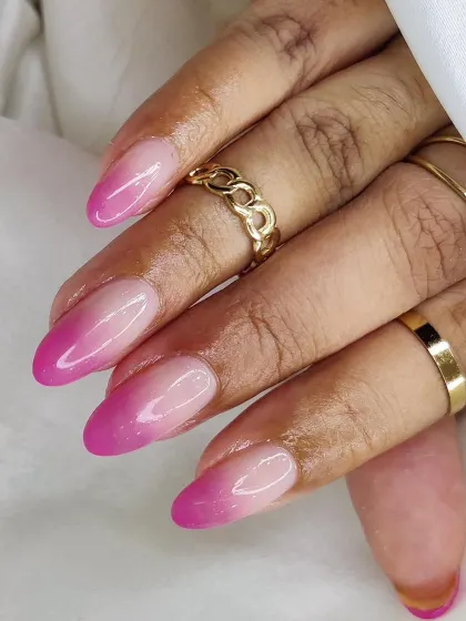 A bright and bold pink ombré on oval-shaped nails. The color fades from a sheer nude at the cuticle to a vibrant magenta at the tip.