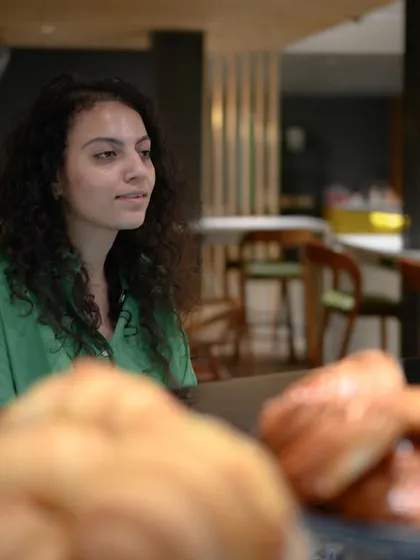 I approached this lady at a new bakery for a quick portrait. This candid shot captures her in her work environment, with the foreground of baked goods adding context. It's a great way to create authentic content for local businesses.