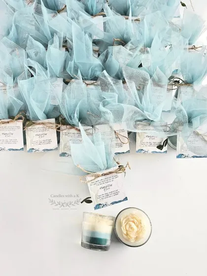 An ocean-themed 'Save-the-Date' gift, featuring a layered votive candle with a peony top, packaged beautifully with a custom card.