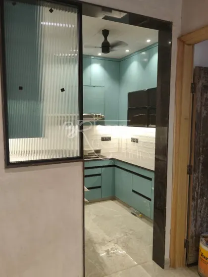 A view from the entrance, showing how the kitchen seamlessly integrates with the rest of the home. The fluted glass partition provides a sense of openness while subtly separating the spaces.