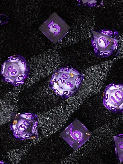 Another shot on black sand, this time for the purple dice set. The dark, granular texture provides a beautiful contrast to the smooth, translucent dice, making their internal swirls and colors appear even more vibrant.