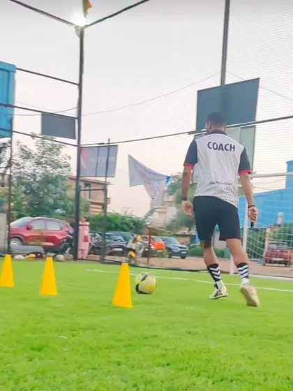 A coach demonstrates a dribbling technique around cones. We believe in leading by example and showing our players the right way to practice.