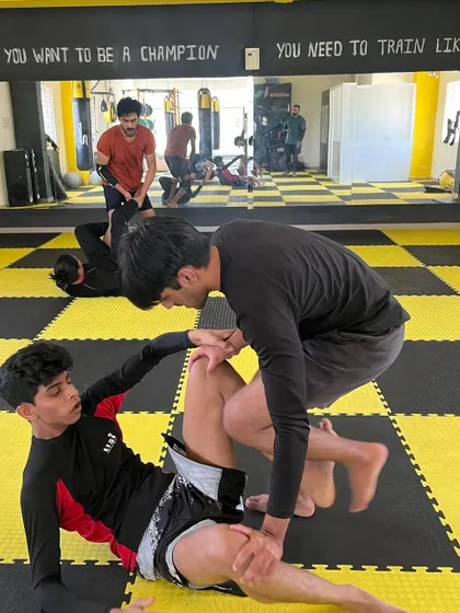 Two students engaged in a technical BJJ roll. The focus is on control and setting up submissions.