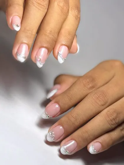 Simple, clean, and elegant. A classic French manicure on natural-length nails, enhanced with a delicate silver line and a single rhinestone for a touch of class.
