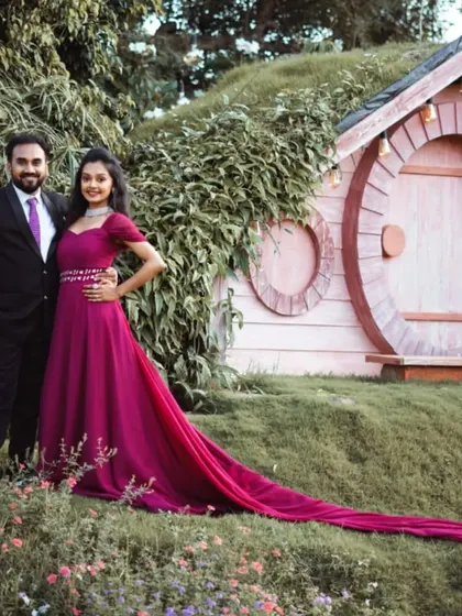 A fairytale setting for a pre-wedding shoot. The client is wearing a magenta gown with a long trail that complements her partner's black suit and purple tie.