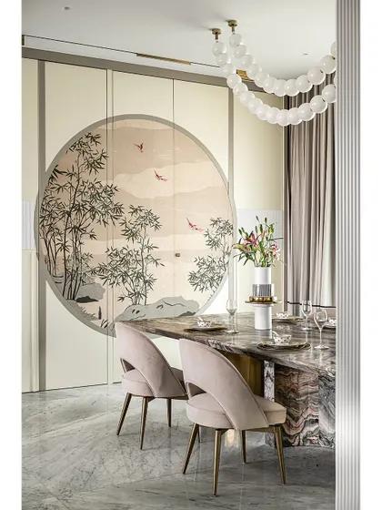 This dining area features a stunning veneer marquetry artwork on pocket shutters, which conceal a spacious crockery unit. The custom marble dining table and soft pink chairs create an elegant setting, while the bubble chandelier adds a touch of modern whimsy.