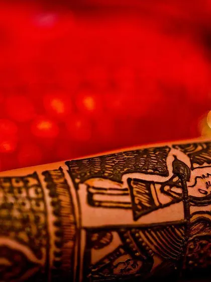 Details tell a story. This close-up of the bride's mehendi isn't just about the henna art; it features a custom doli design, a deeply personal and meaningful element of her wedding story, captured with a sharp macro perspective.