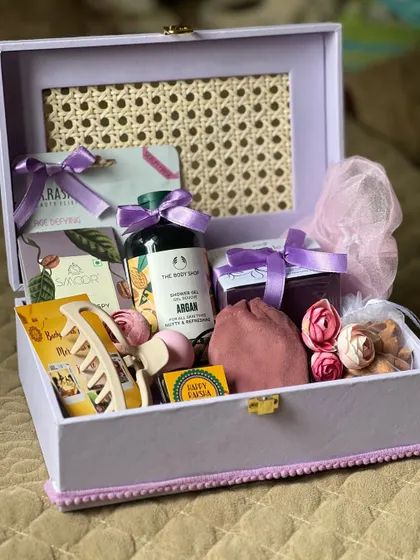 A luxurious Rakhi hamper for a sister in a lavender trunk box. It's filled with premium self-care items like The Body Shop shower gel.