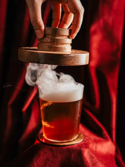 Creating atmosphere for a smoked cocktail at Amelia. We used dramatic lighting against a rich, red velvet background to highlight the billow of smoke, turning a simple drink into a theatrical experience and an unforgettable visual.