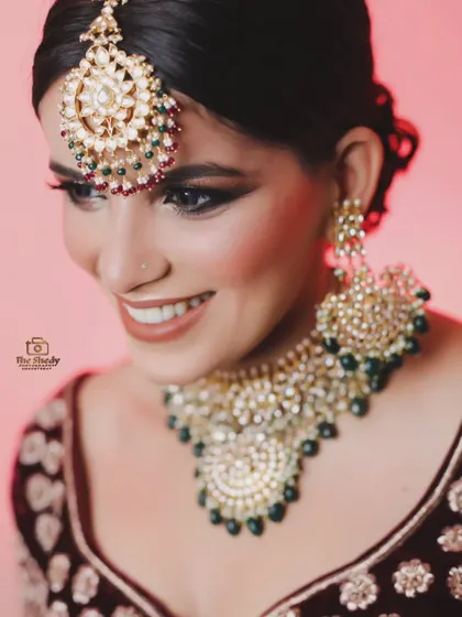 A close-up shot of a smiling bride, showcasing her beautiful Kundan jewelry set with green beads. We capture the happiness and the details.