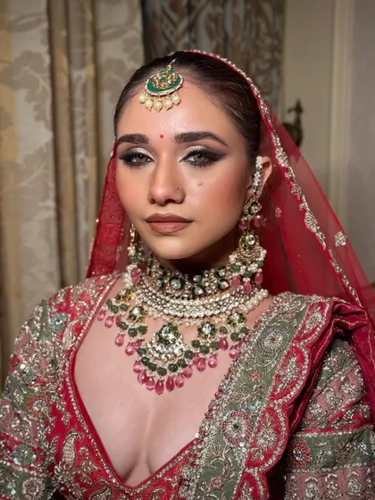 Here you can see the power of a perfectly defined eye and a flawless base. The red dupatta frames the face, making the makeup pop and creating that iconic bridal portrait.