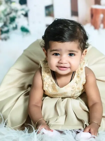 A 'Winter Wonderland' theme is perfect for a festive Christmas photoshoot. This baby girl looks adorable in her golden dress against a snowy, magical backdrop.