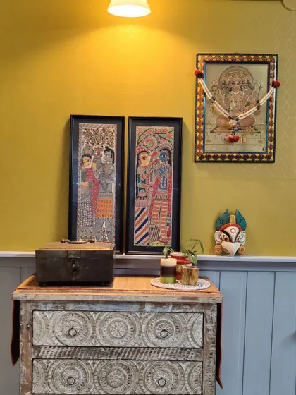 This little corner is dedicated to prayer and peace. I used a carved wooden chest of drawers as a base for displaying traditional Madhubani paintings and a Tanjore artwork, creating a personal and spiritual nook.