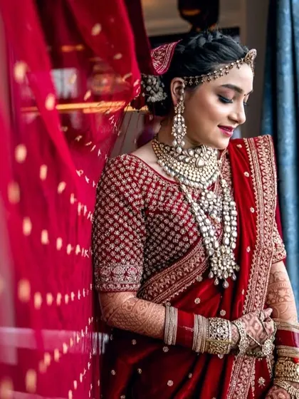 A stunning portrait of the bride in her red wedding lehenga, framed by a soft red veil, creating a dreamy and romantic effect.
