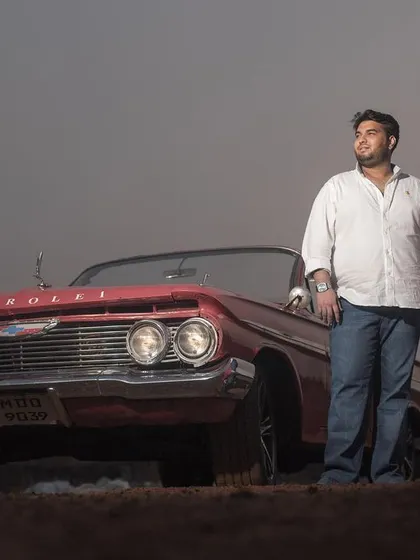 A moody and atmospheric shot of the couple with a vintage car at dusk, creating a romantic and dramatic pre-wedding portrait.