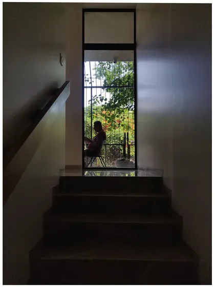 A view up a flight of stairs towards a door that opens to the outside. The silhouette of a person enjoying the view creates a sense of peace and connection to the outdoors.