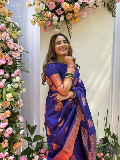 A happy bridesmaid posing against a floral backdrop. Her makeup and hair look perfect for the wedding festivities.