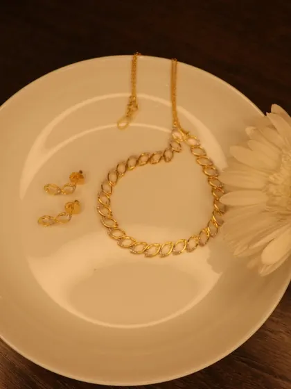 A perfect gift for a loved one, or for yourself. This delicate necklace set, with its twisting diamond design, is beautifully presented on a plate with a white flower. It's simple, elegant, and budget-friendly.