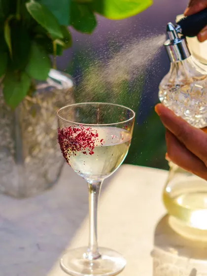 The final flourish. A spritz of aromatic bitters adds a layer of complexity and visual flair to this elegant, clear cocktail.