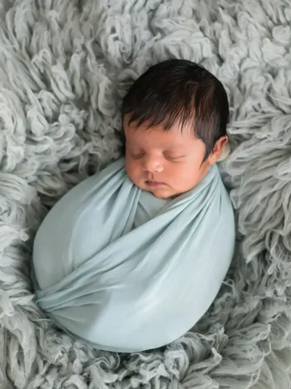 A perfectly wrapped newborn, looking like a tiny, cozy bean. This classic "potato sack" pose is a favorite for showing how small and curled up they are in their first few weeks.