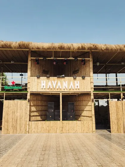 The completed facade of Havanah in Faridabad, featuring a rustic and tropical look achieved with bamboo cladding and a thatched roof, complemented by our landscaping.