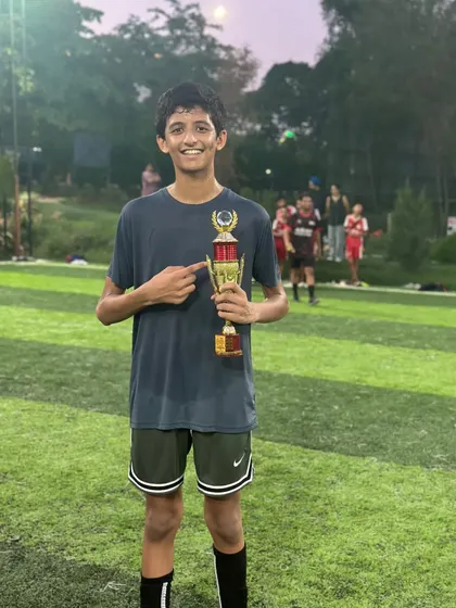 This player proudly points to his trophy, a symbol of his dedication and skill on the field.