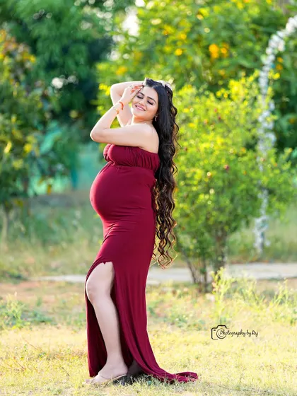 A radiant mother-to-be in a simple yet elegant red fabric wrap, enjoying the sunshine in our private garden.