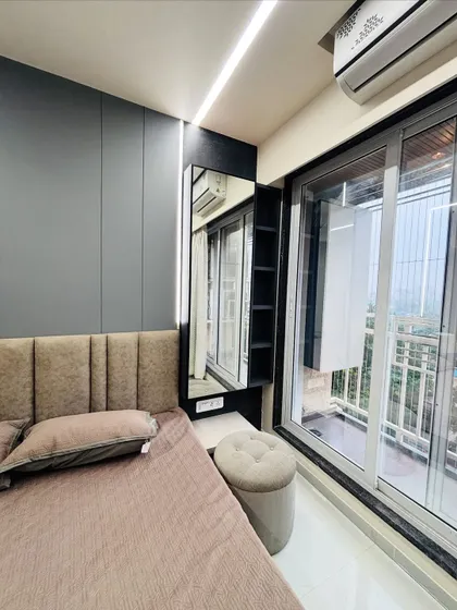A space-saving dressing nook carved out next to the window, complete with a full-length mirror, a small counter, and a comfortable pouf.